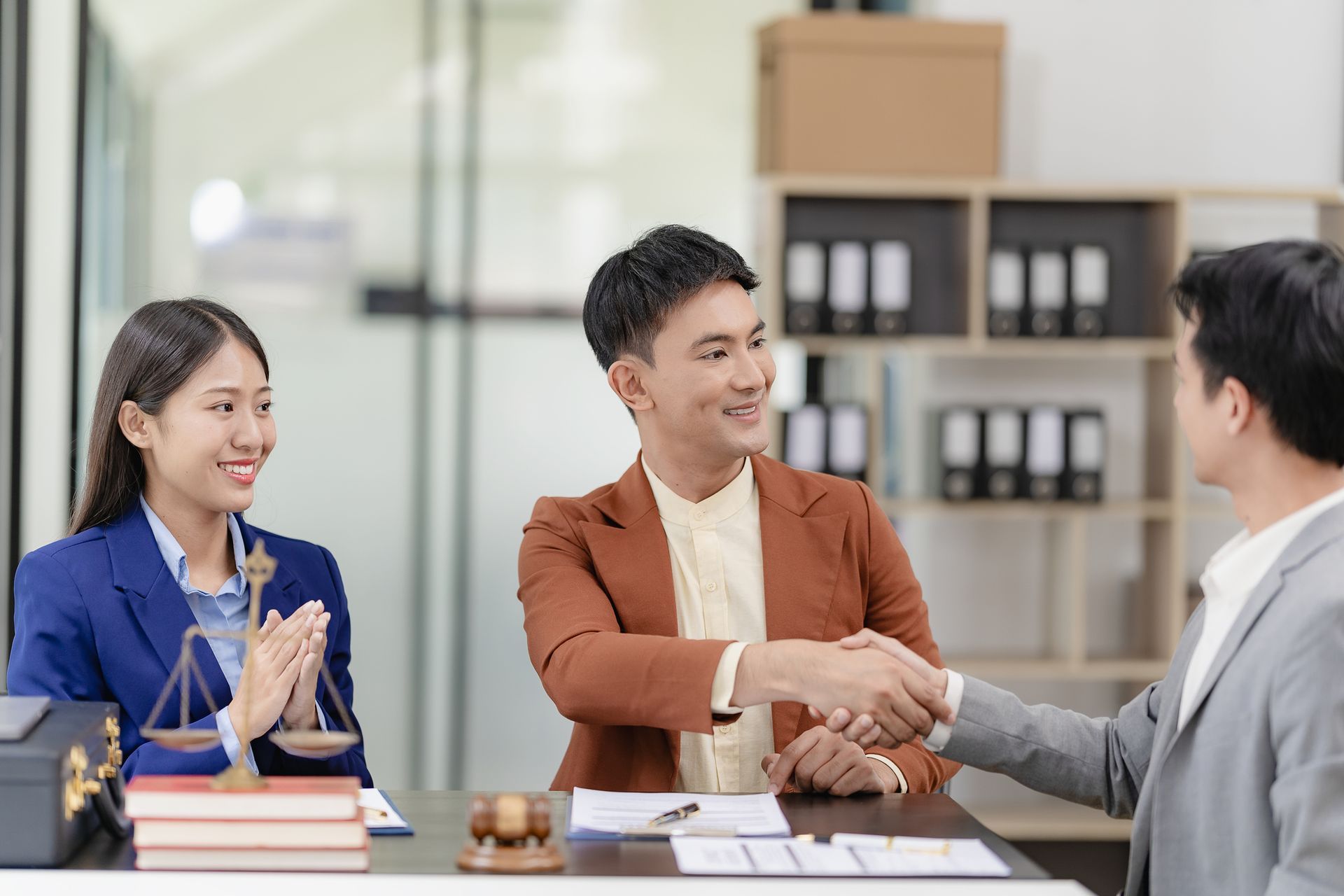 A man and a woman are shaking hands with a lawyer in an office.