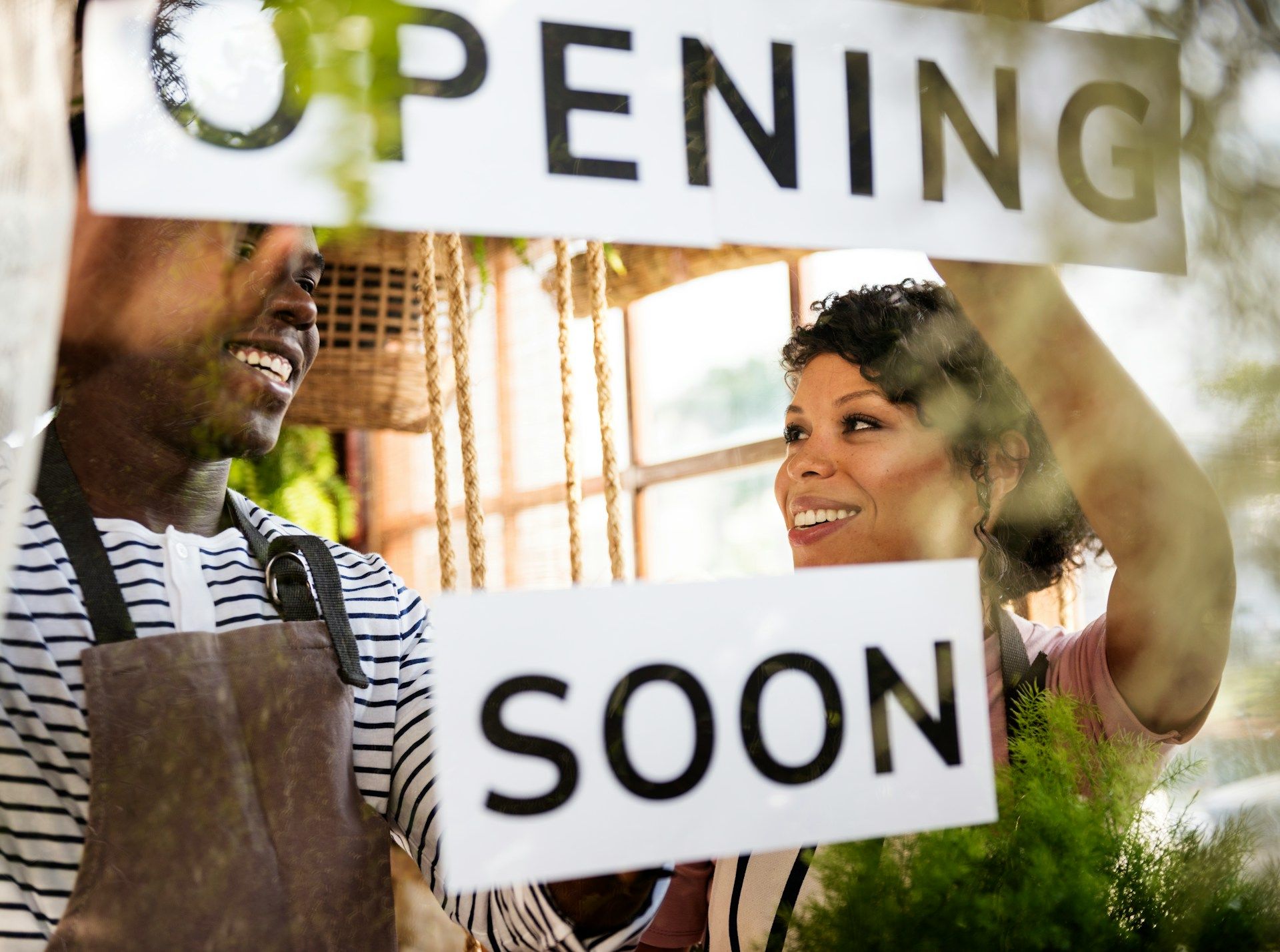 People placing “OPENING SOON” signs on a storefront window