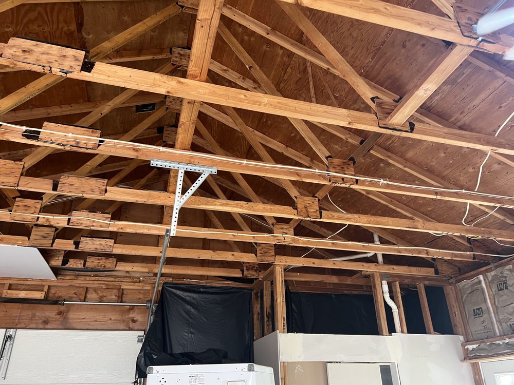 Exposed wooden attic rafters and roof trusses inside an unfinished room with insulation and covered openings