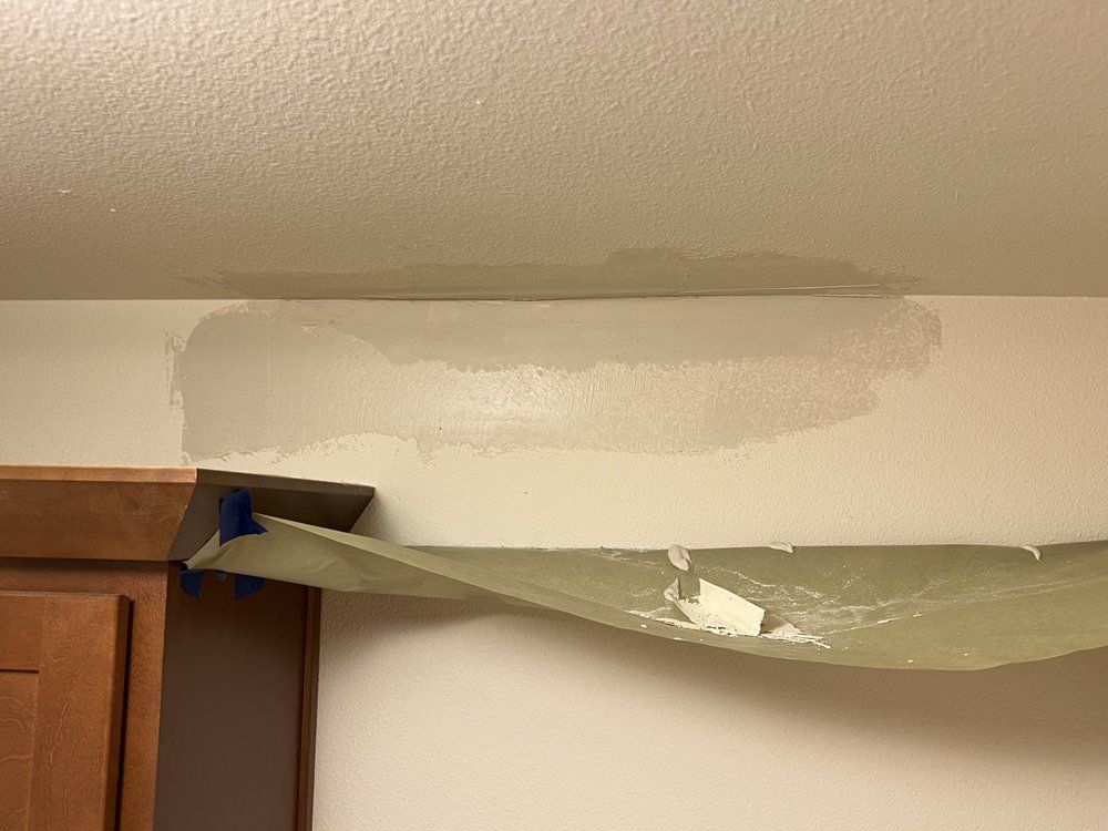 Painter’s tape and plastic sheeting covering a wall ceiling crack during repair