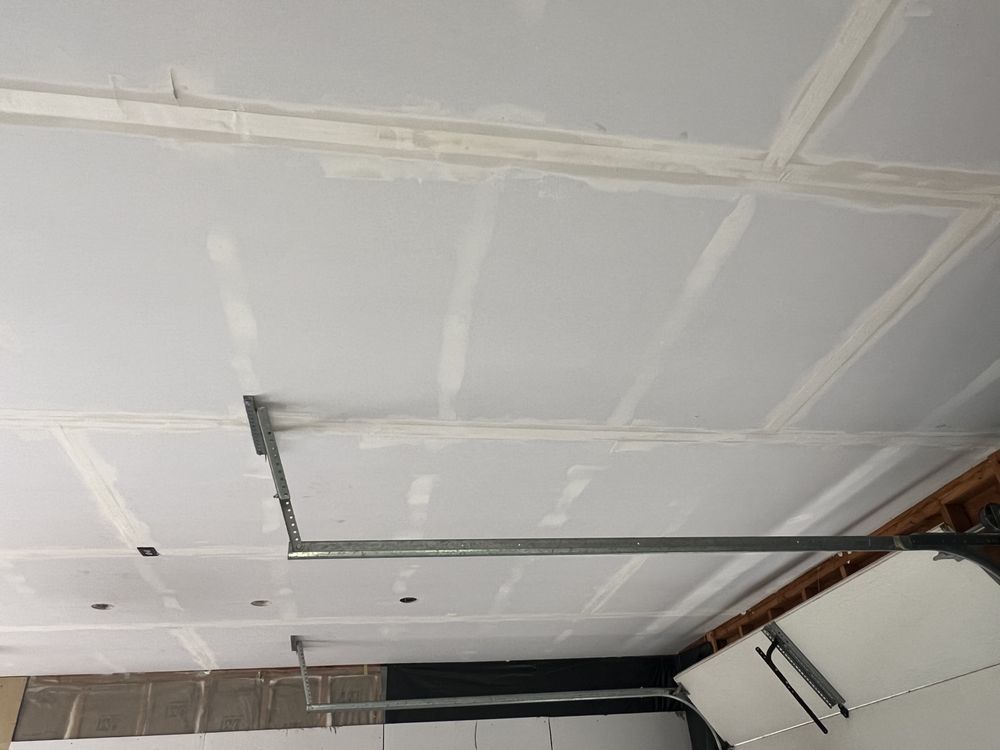 White ceiling with exposed pipes and a damaged section near a wall, viewed indoors