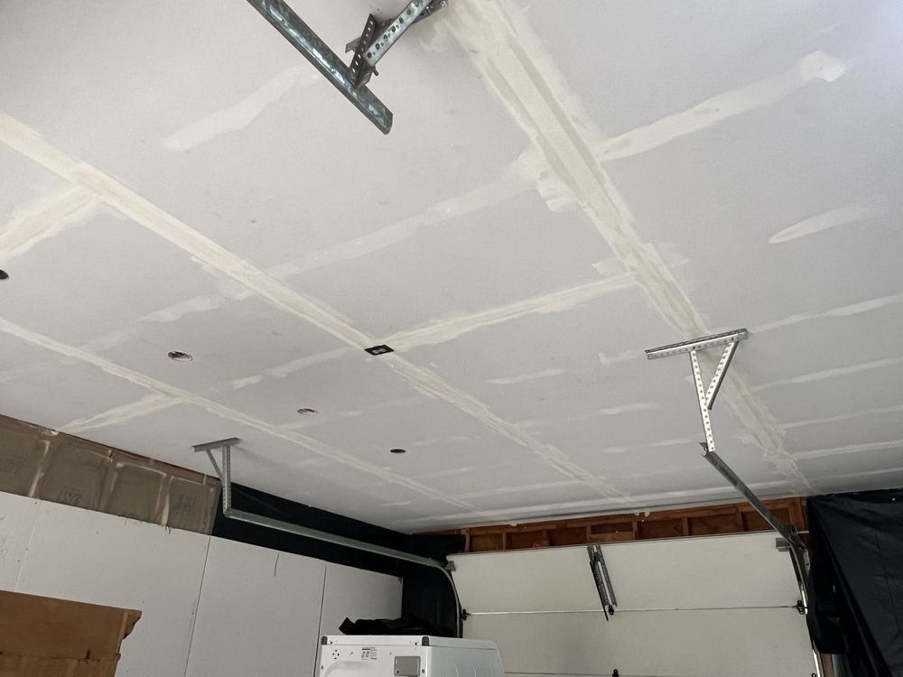 Garage ceiling with drywall seams and hanging metal tracks, likely under construction or repair