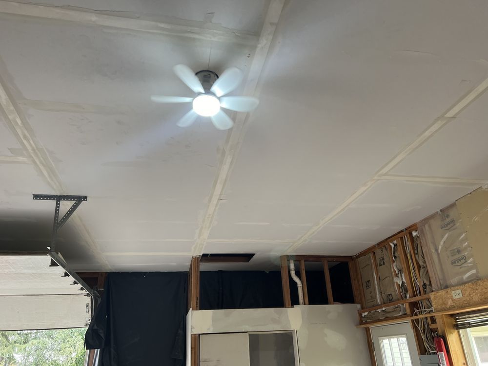 Garage interior with a white ceiling fan, exposed framing, and stacked boxes along the wall