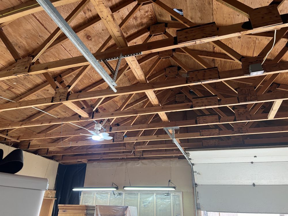 Interior garage with exposed wooden truss ceiling and hanging fluorescent lights