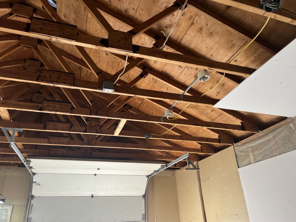 Garage interior with exposed wooden rafters and a partially open garage door