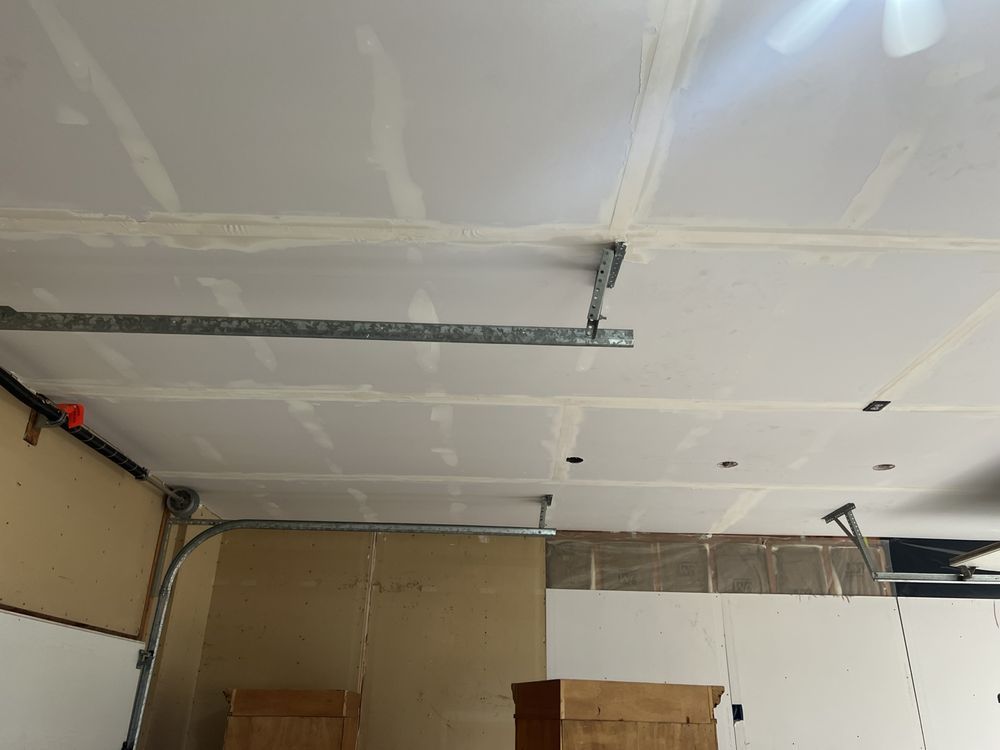Garage ceiling under construction with taped drywall seams, metal tracks, and exposed wiring