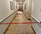 Narrow hallway with a damaged floor, blocked by red caution tape
