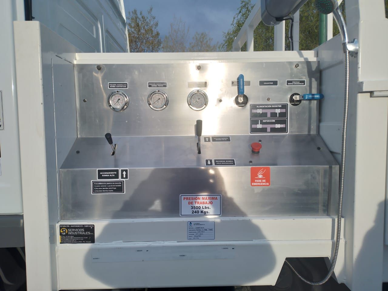 Panel de control eléctrico metálico con indicadores, interruptores y etiquetas de advertencia en una unidad exterior.