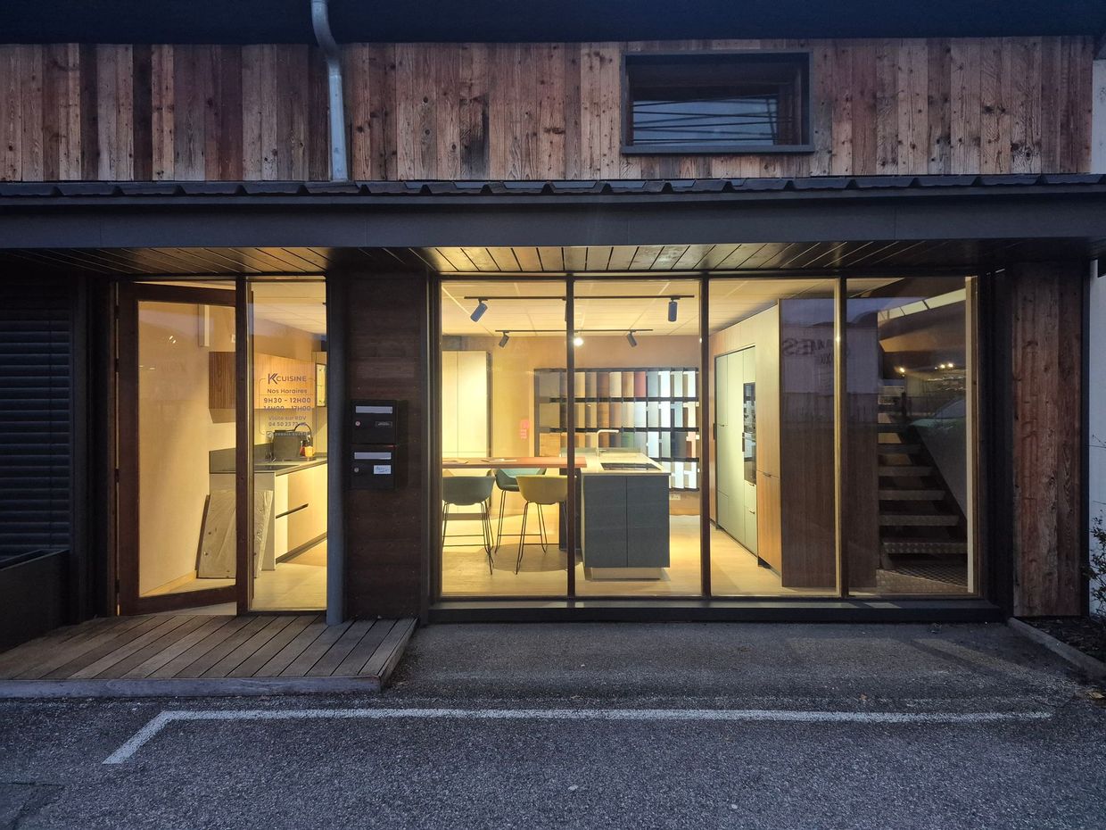 Façade moderne avec intérieur éclairé à la lumière chaude, portes vitrées et façade en bois au crépuscule
