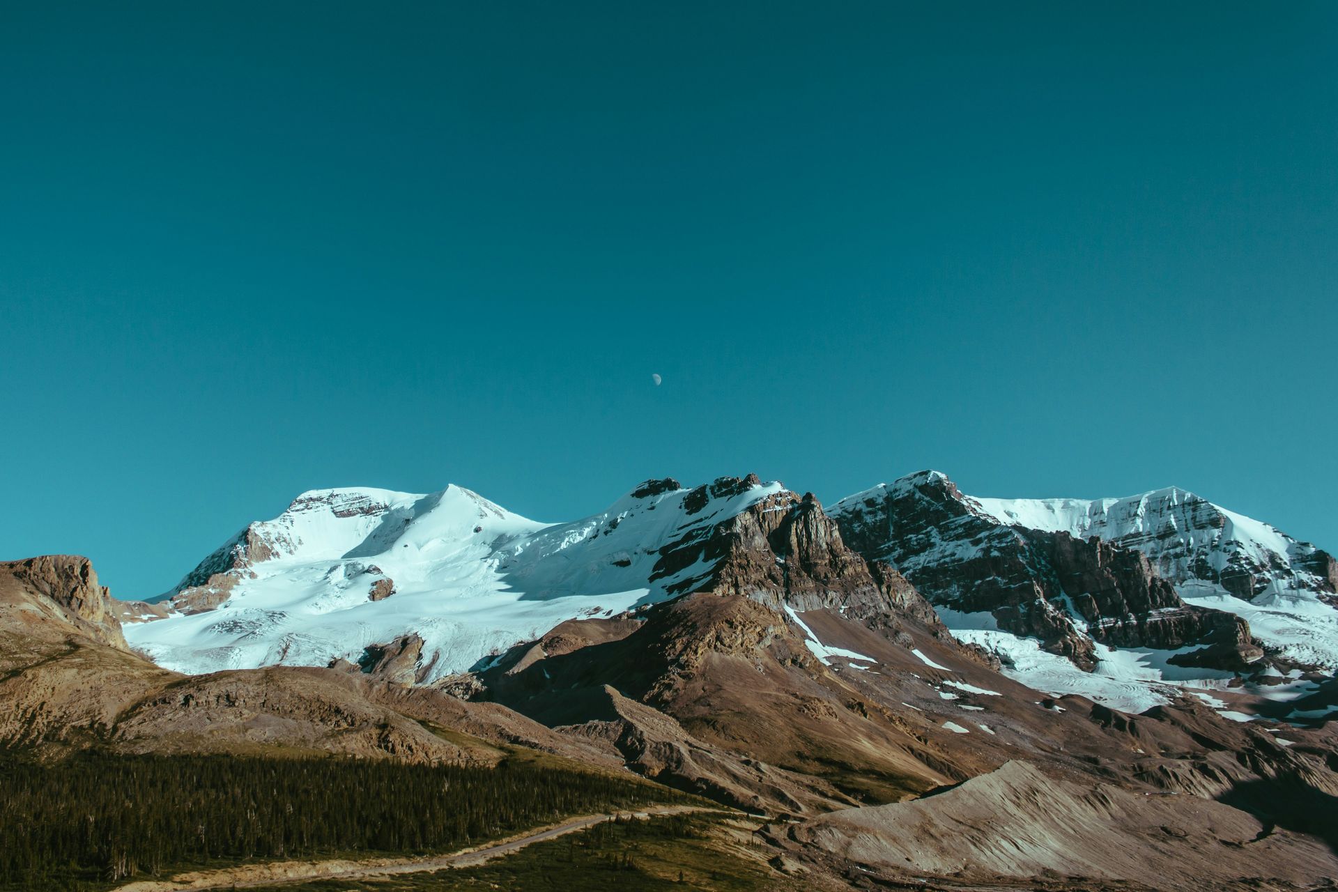 Snow-covered mountain range beneath a clear turquoise sky