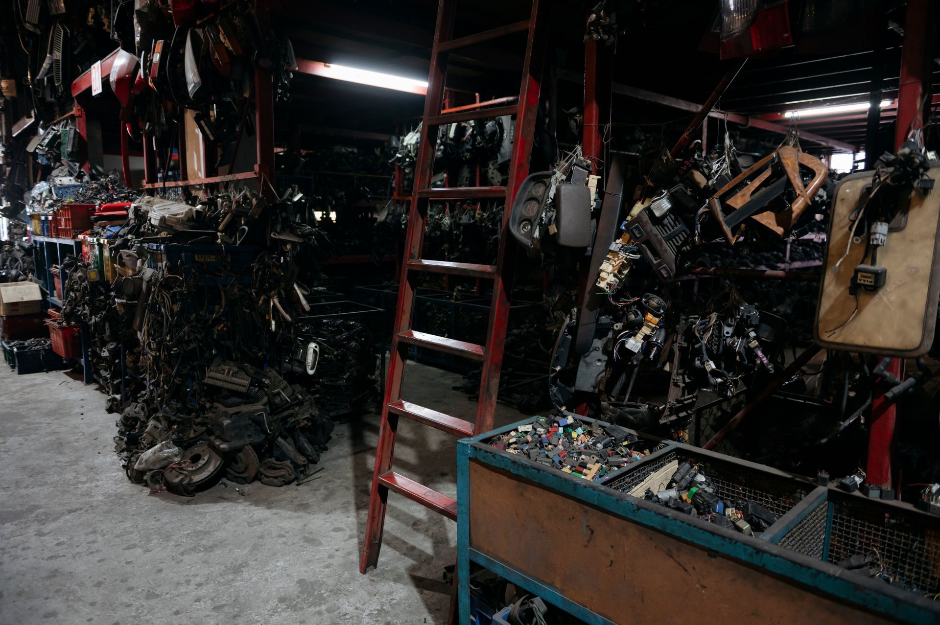 Shelves and bins filled with various used auto parts in a large, organized salvage yard warehouse.