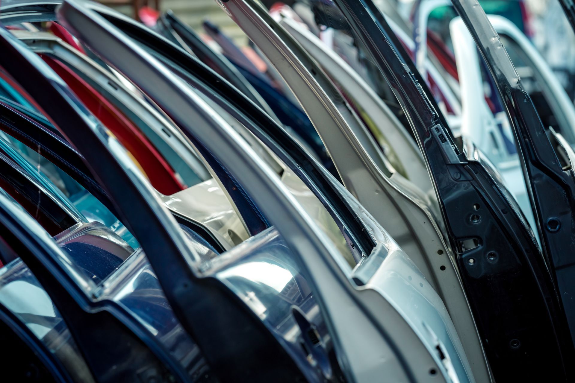 Rows of used car doors in assorted colors lined up at a junkyard