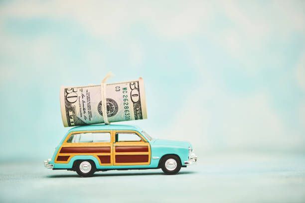 Toy vintage station wagon with cash roll on roof symbolizes quick cash for unwanted or junk vehicles