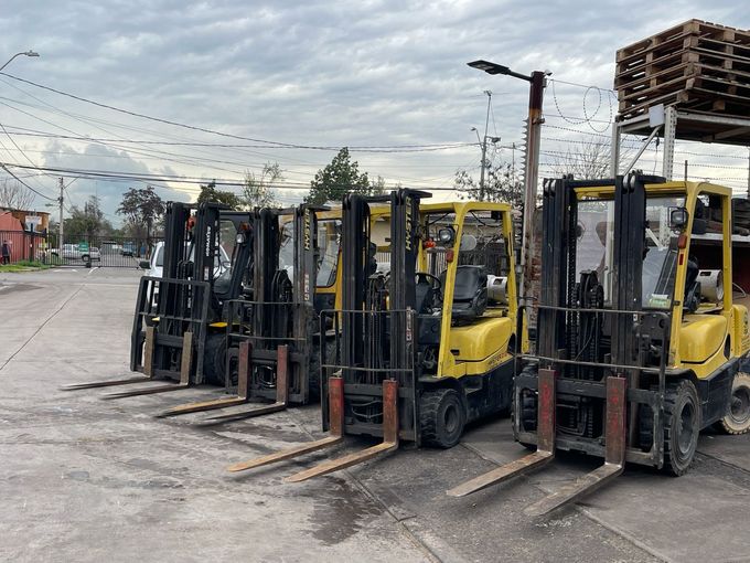Una carretilla elevadora cargaba palés apilados en un camión blanco de plataforma junto a un almacén de ladrillos.