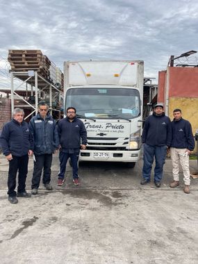 Camioneta blanca de servicio estacionada junto a un almacén en una calle con niebla.