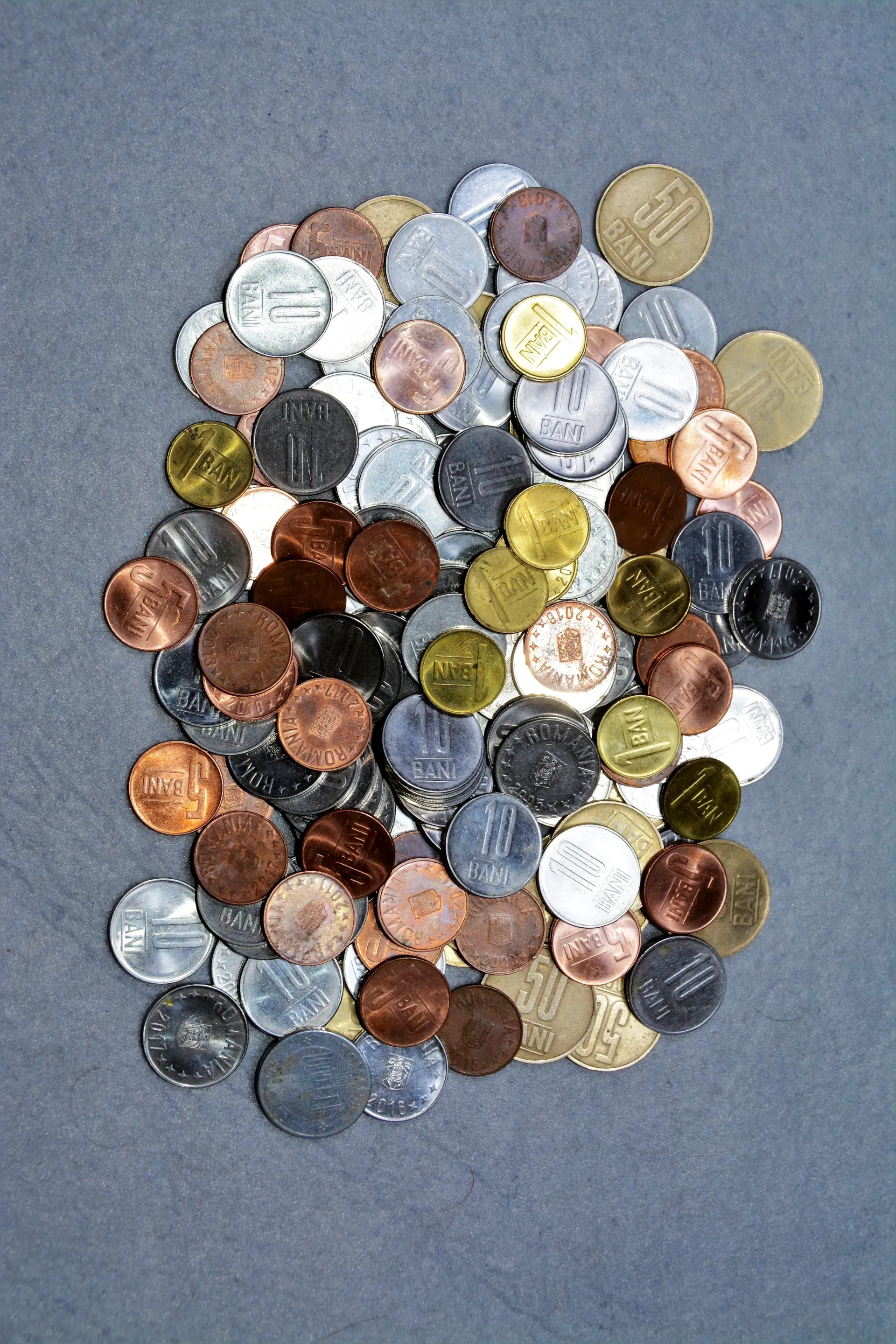 Assorted mixed coins piled on a gray surface