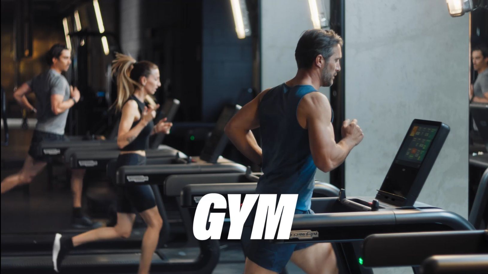 Three people run on treadmills in a modern, brightly lit gym. The word 