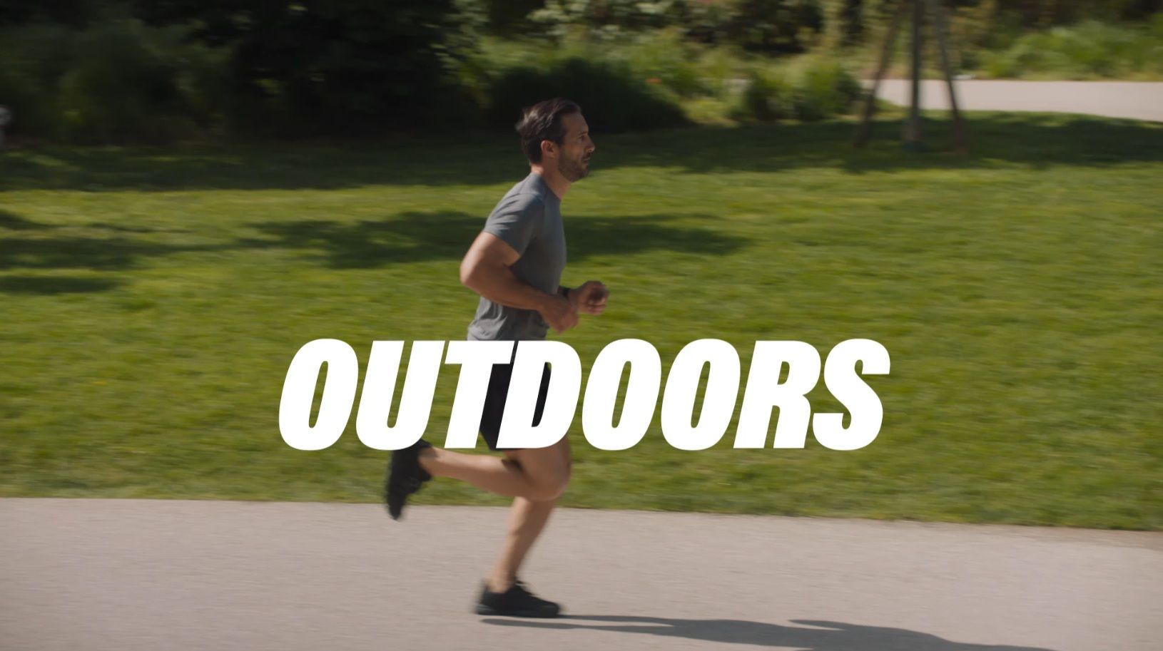 A person jogging on a paved path in a green park with the word 