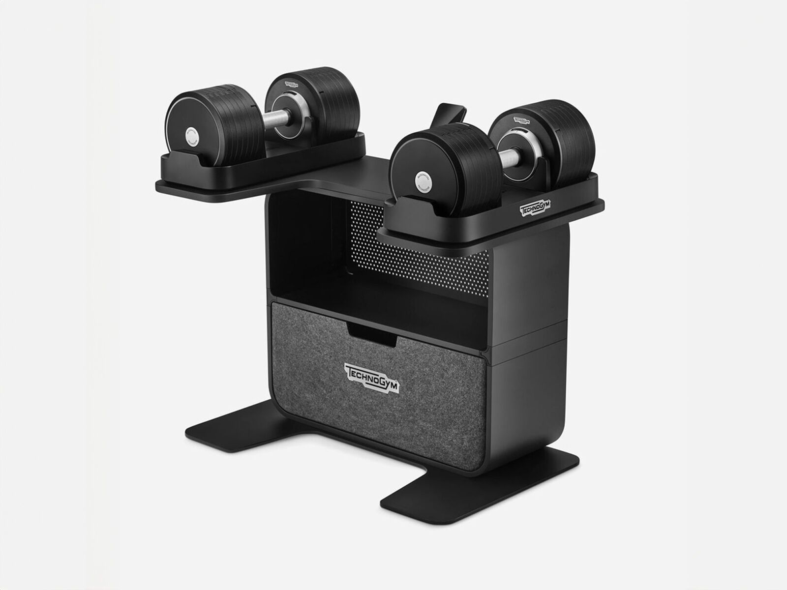 Black Technogym adjustable dumbbells resting on a matching storage rack with a central shelf and drawer.
