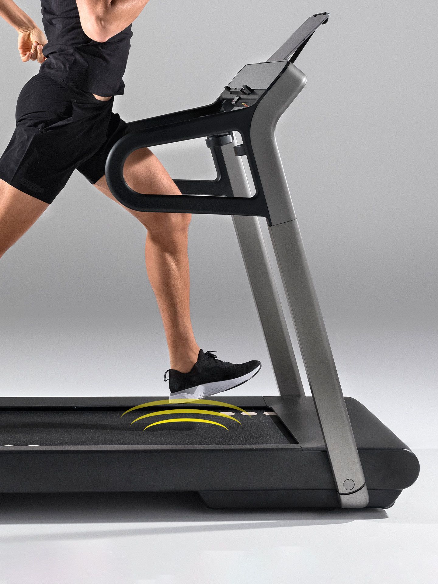 A person running on a treadmill, with yellow motion lines indicating impact on the surface.