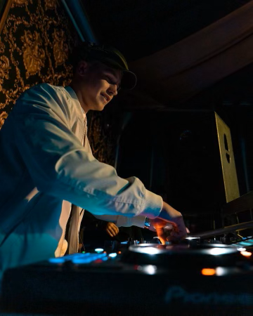 A man in a hat is playing music on a turntable in a dark room.