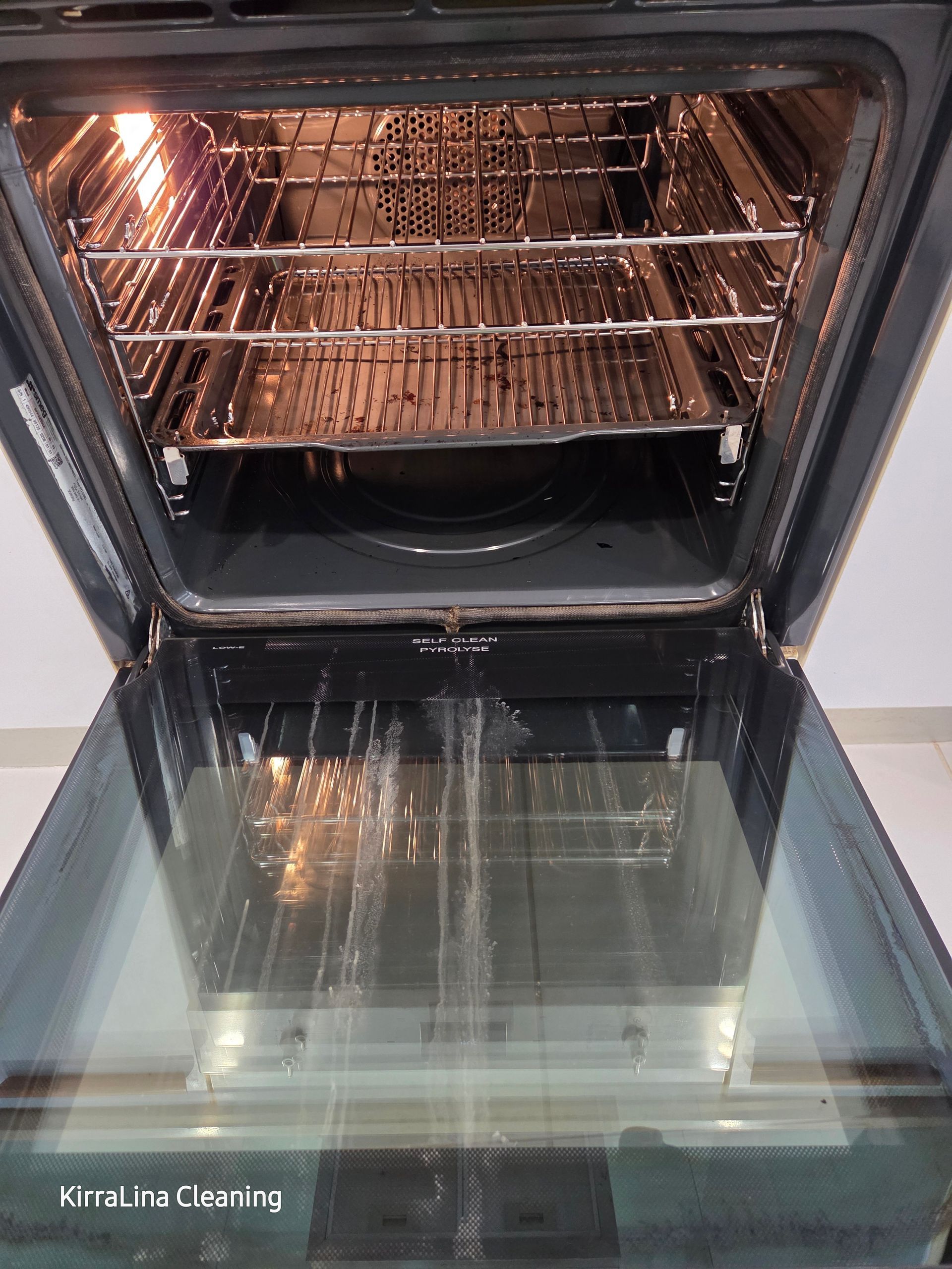 An Open, Empty Oven Interior with Metal Racks and A Glass Door Reflecting the Room Light — KirraLina Cleaning Services in Tweed Heads, NSW
