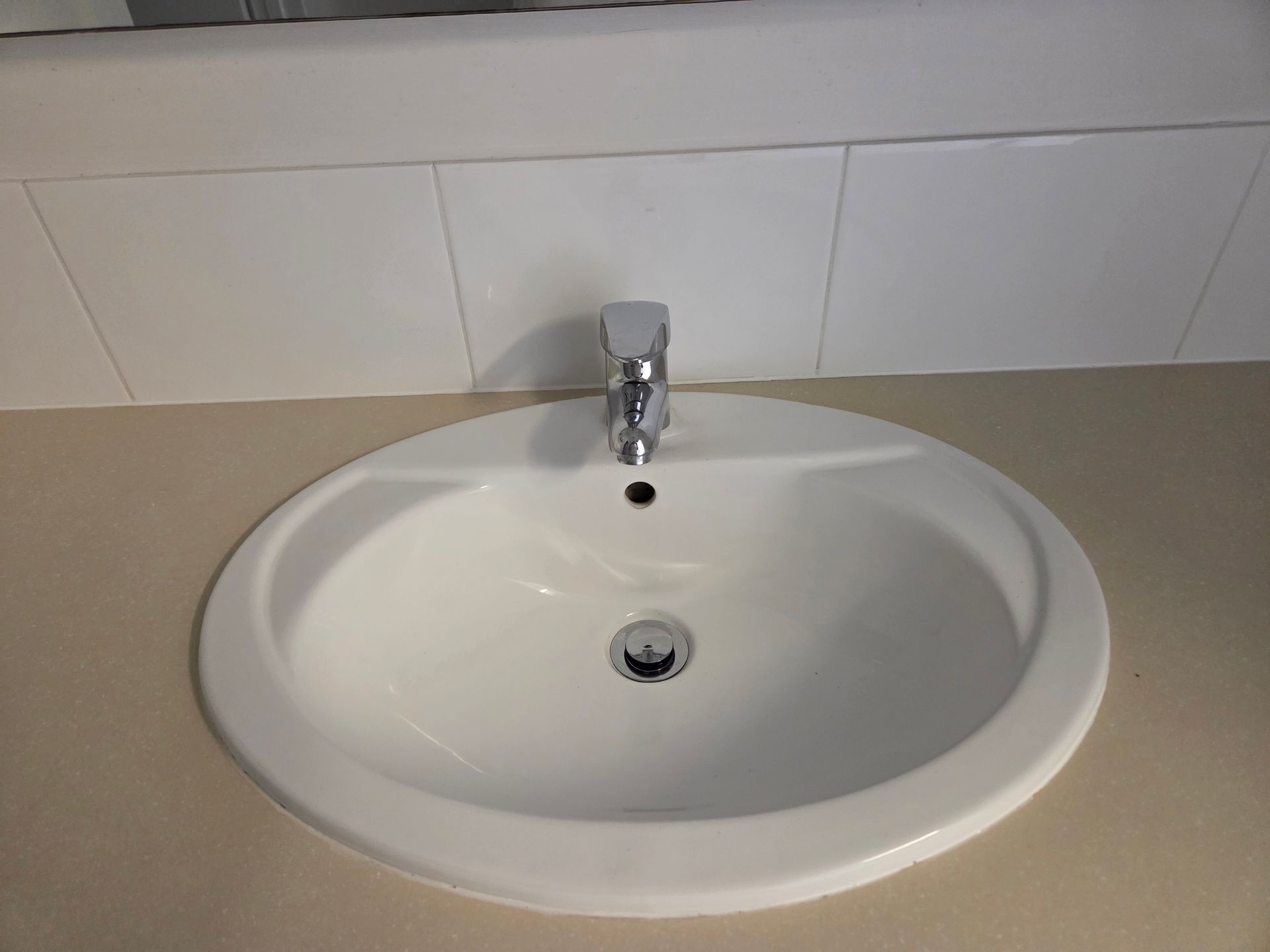 White Bathroom Sink with Chrome Faucet and Tiled Backsplash — KirraLina Cleaning Services in Tweed Heads, NSW