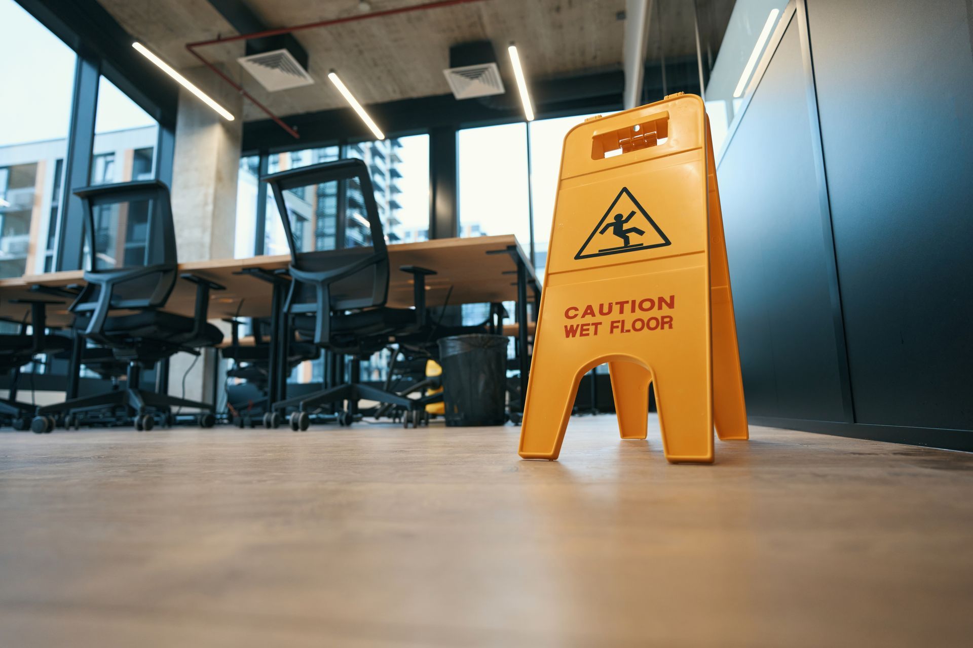 Yellow Wet Floor Sign in a Modern Office With Chairs and Tables — KirraLina Cleaning Services in Banora Point, NSW