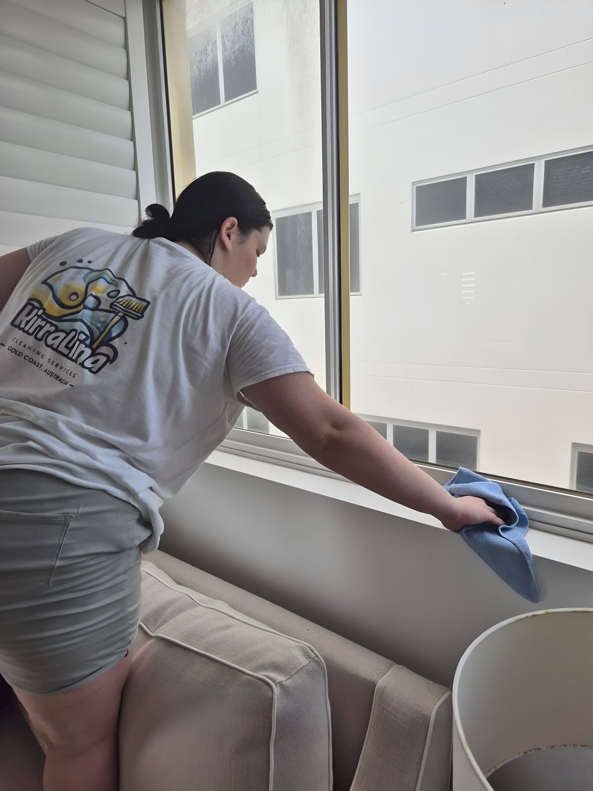 A Woman Is Cleaning a Window — KirraLina Cleaning Services in Gold Coast, QLD