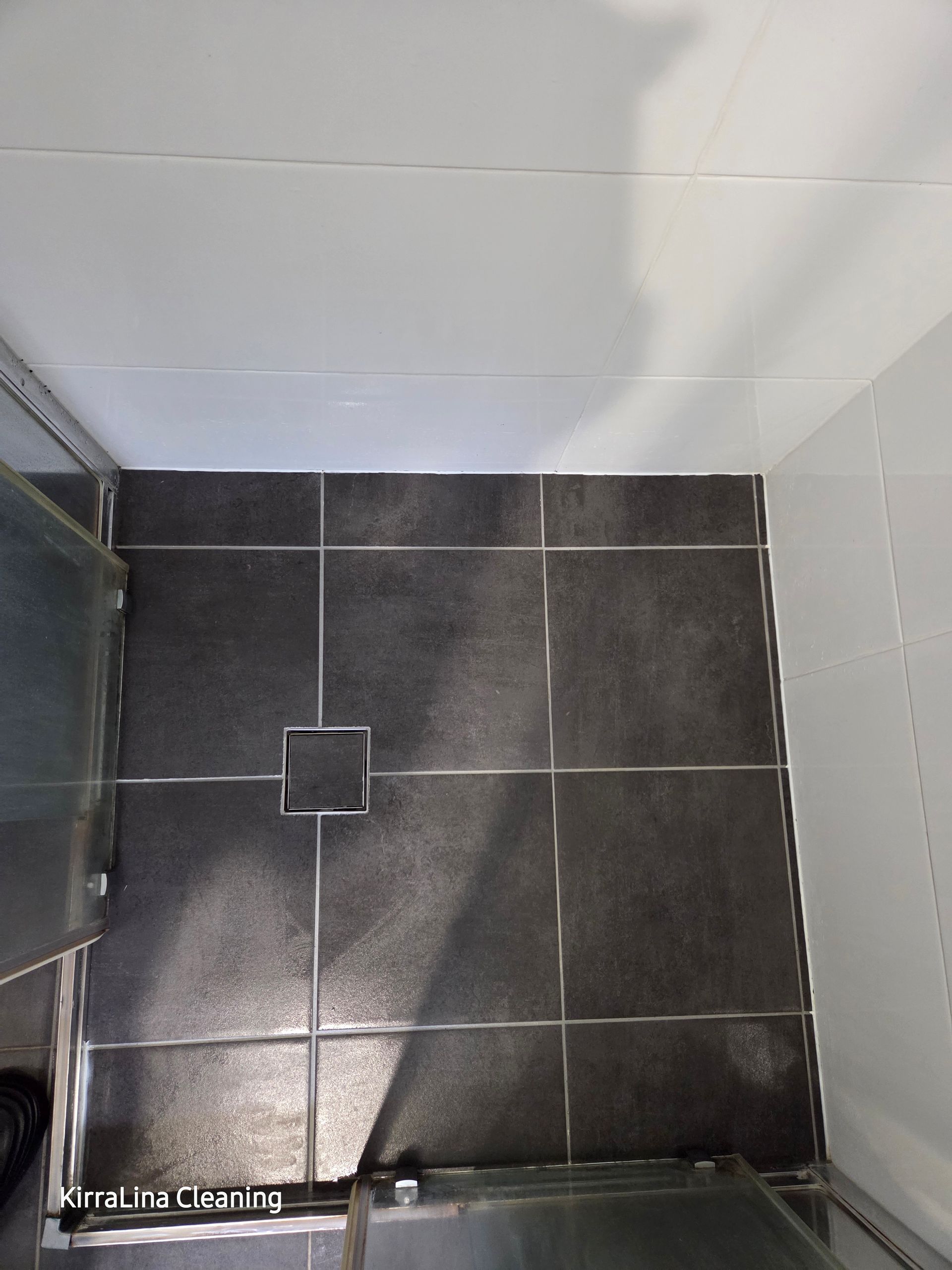 Top-down View of a Small Tiled Shower Floor With a Central Drain and White Walls — KirraLina Cleaning Services in Tweed Heads, NSW