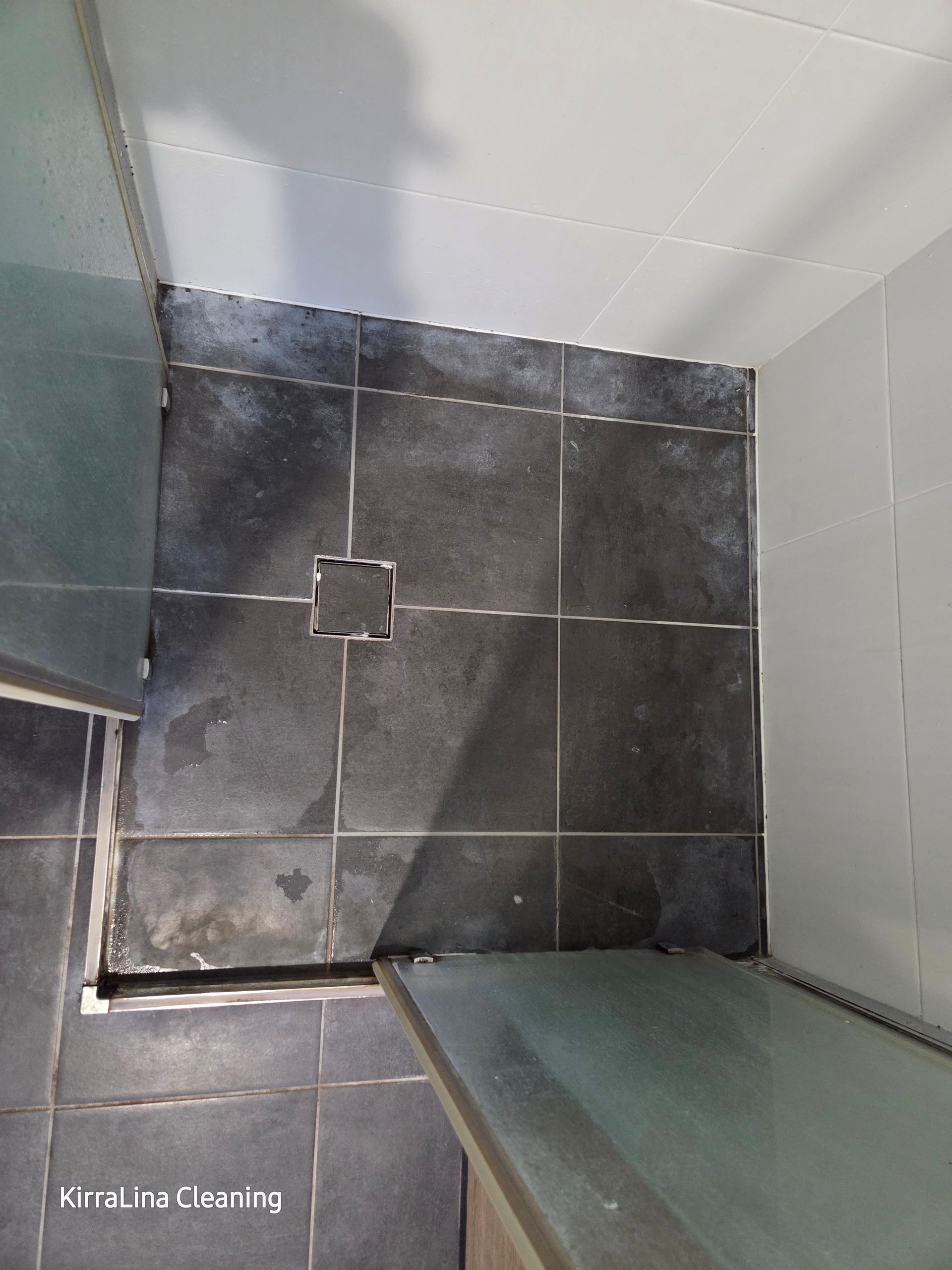 Dark Tiled Shower Floor With a Square Drain and Gray Walls — KirraLina Cleaning Services in Tweed Heads, NSW