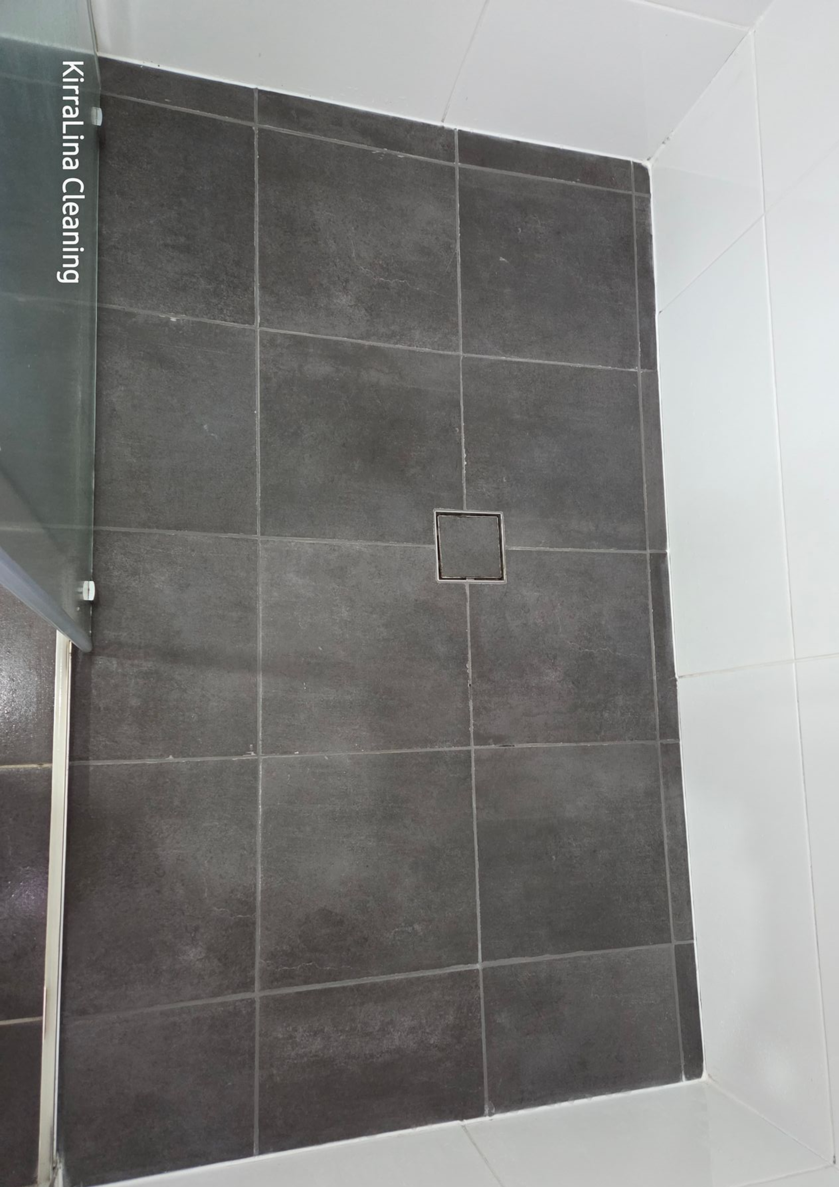 Black-tiled Shower Wall With a Central Square Drain and White Surrounding Tiles — KirraLina Cleaning Services in Tweed Heads, NSW