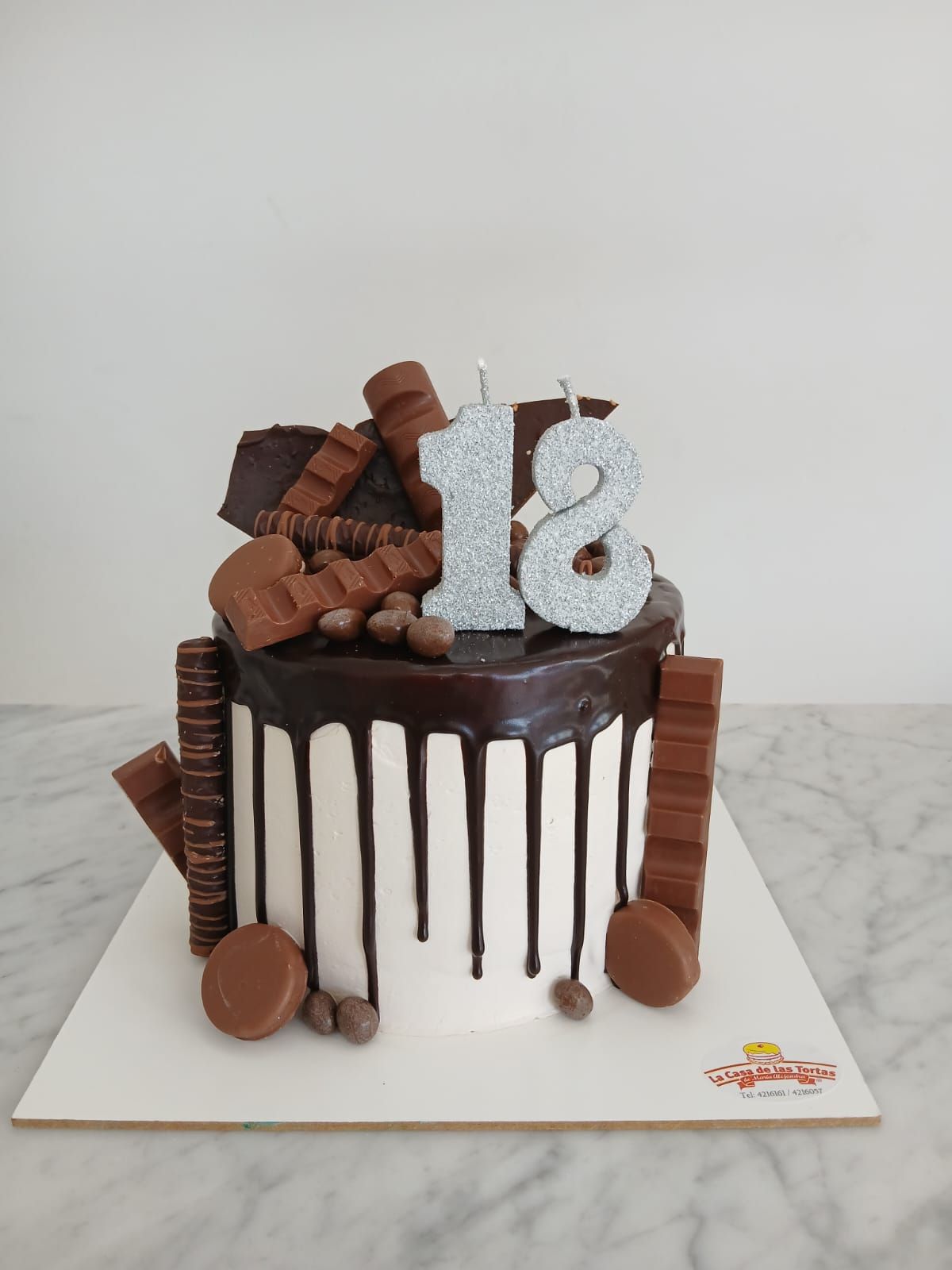Pastel de chocolate con glaseado chorreante, adorno blanco con el número 