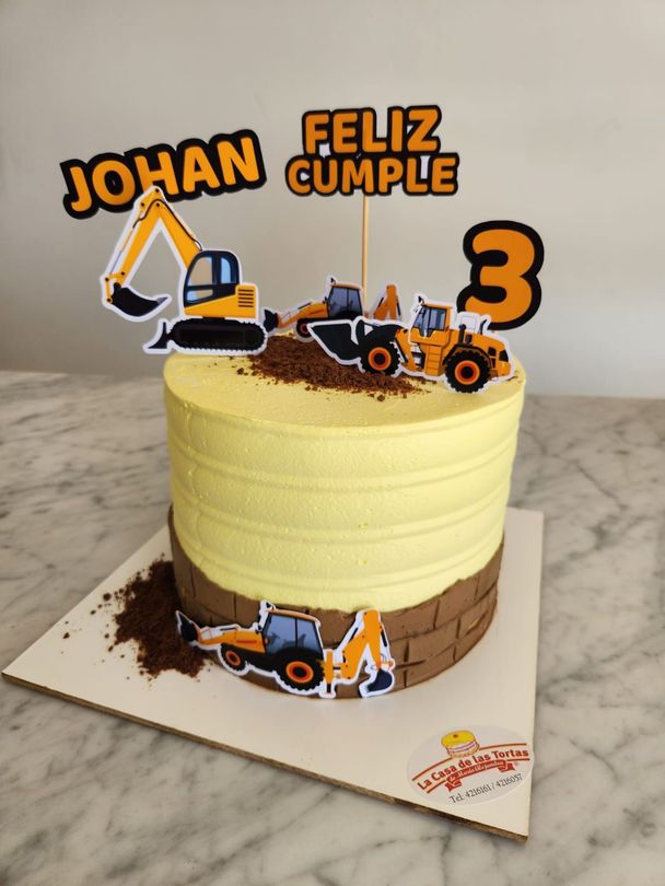 Tarta de cumpleaños amarilla con adornos con temática de construcción, excavadoras de juguete.