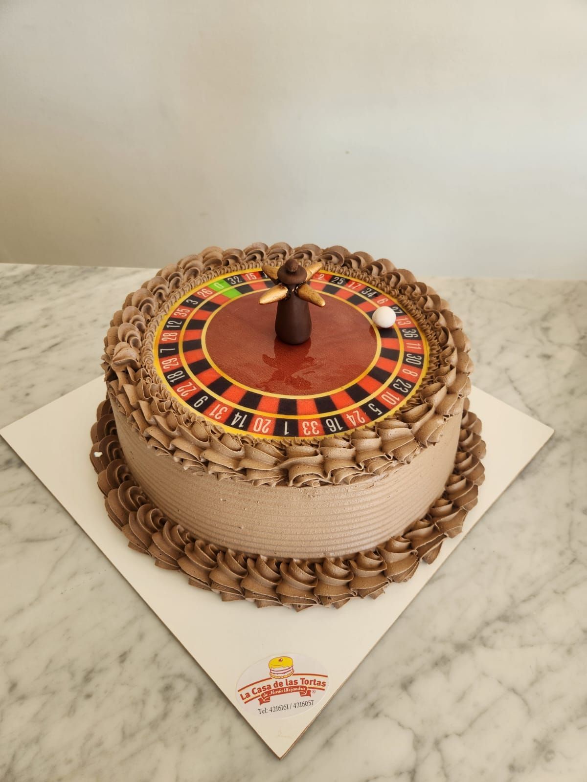 Tarta redonda decorada con un diseño en naranja y marrón en la parte superior, sobre una base blanca para tartas.