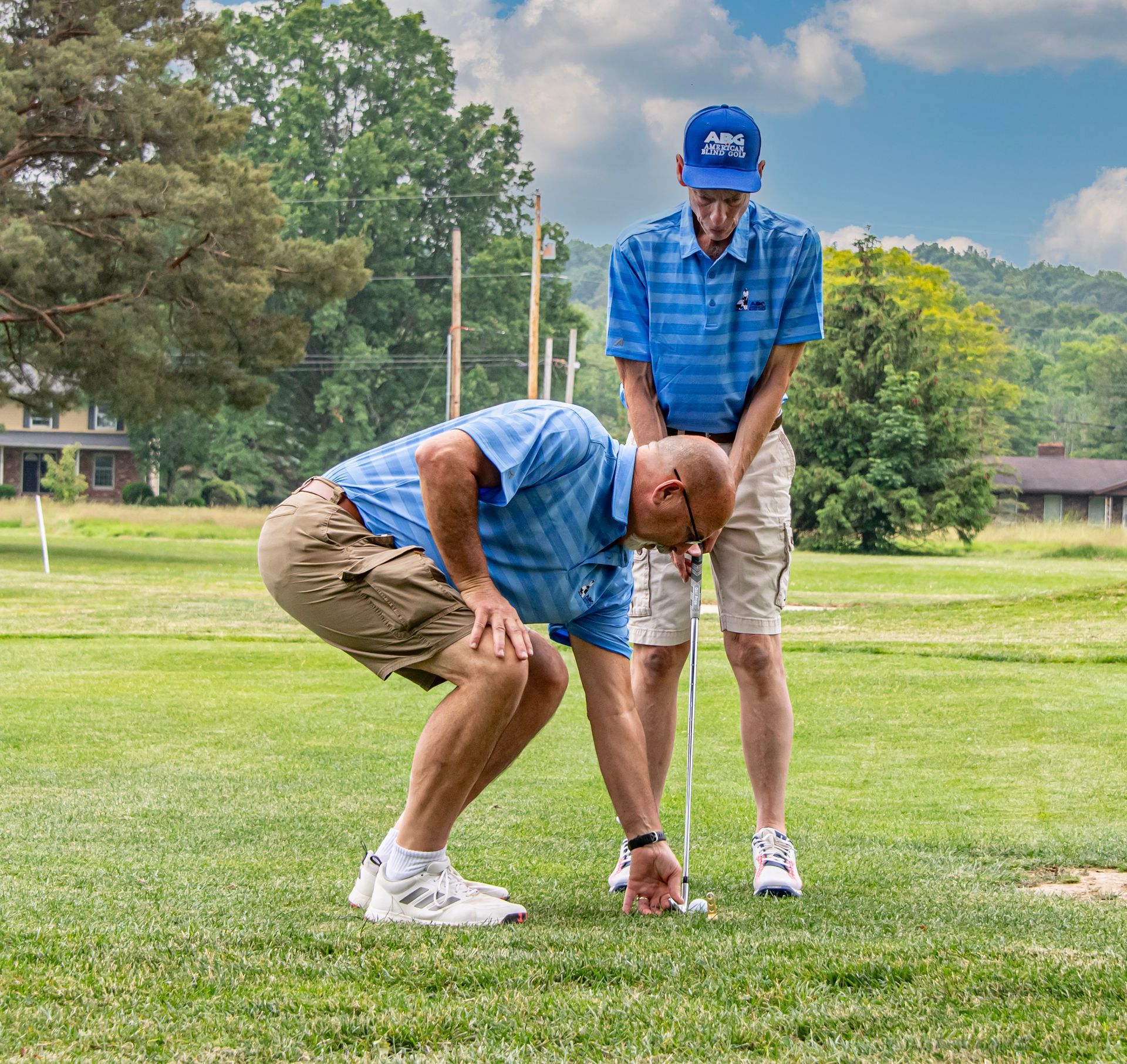 A blind golfer getting ready to tee off with the help of his spotter