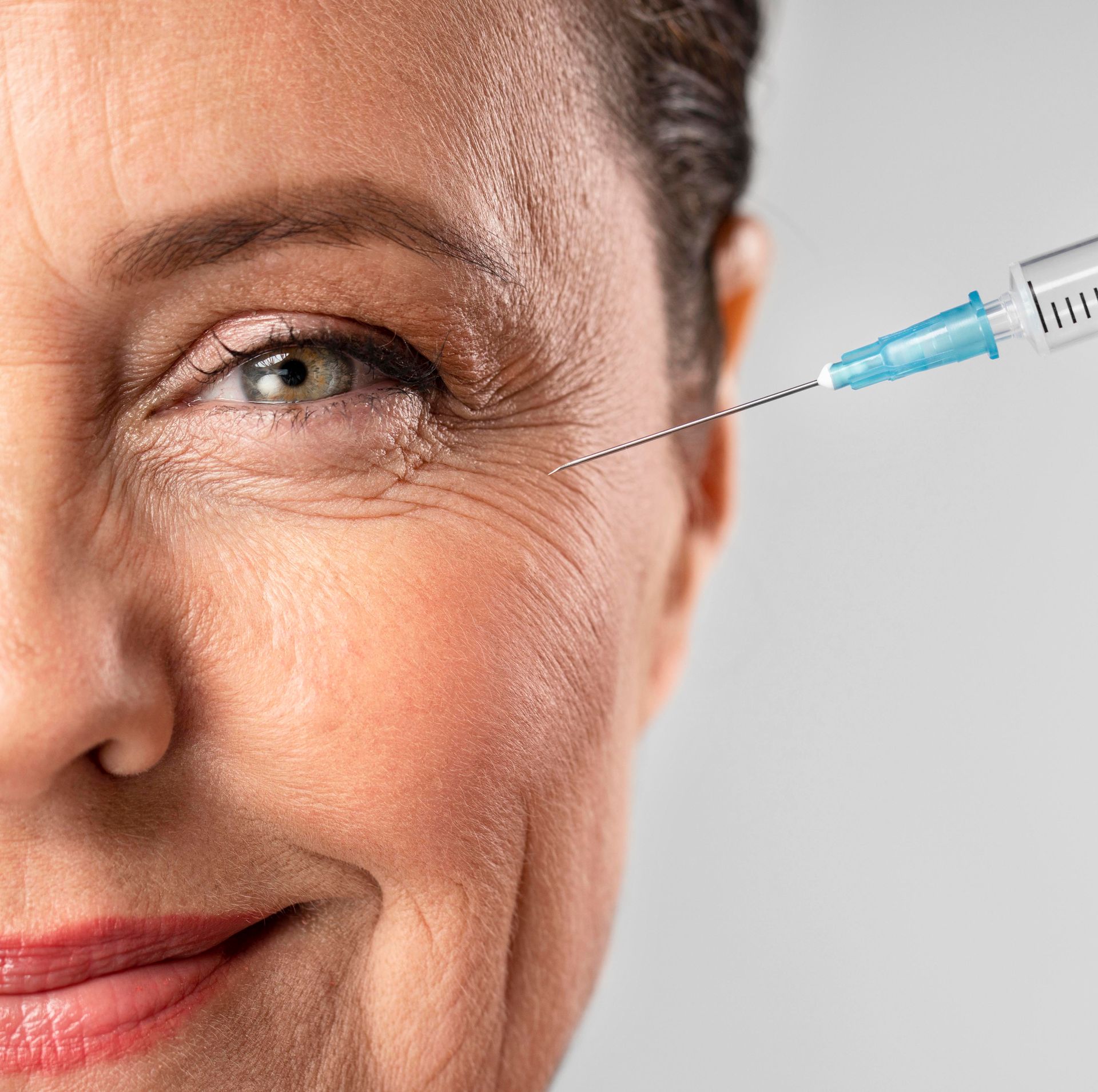 Woman receiving injection near eye to reduce wrinkles.