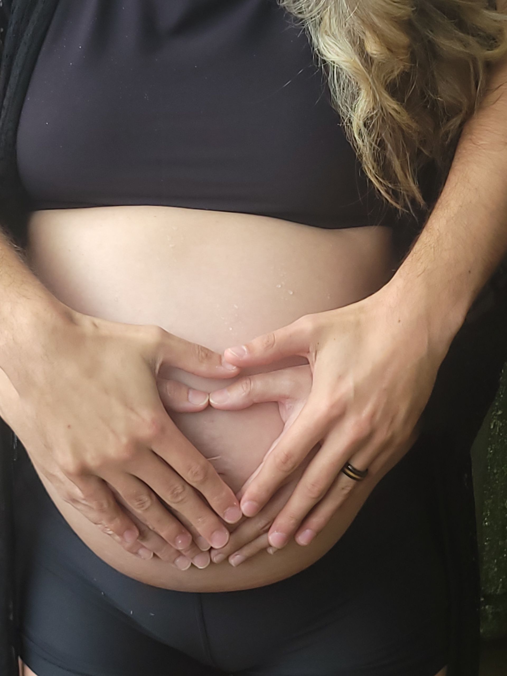 mom and dad hand hearts on pregnant belly