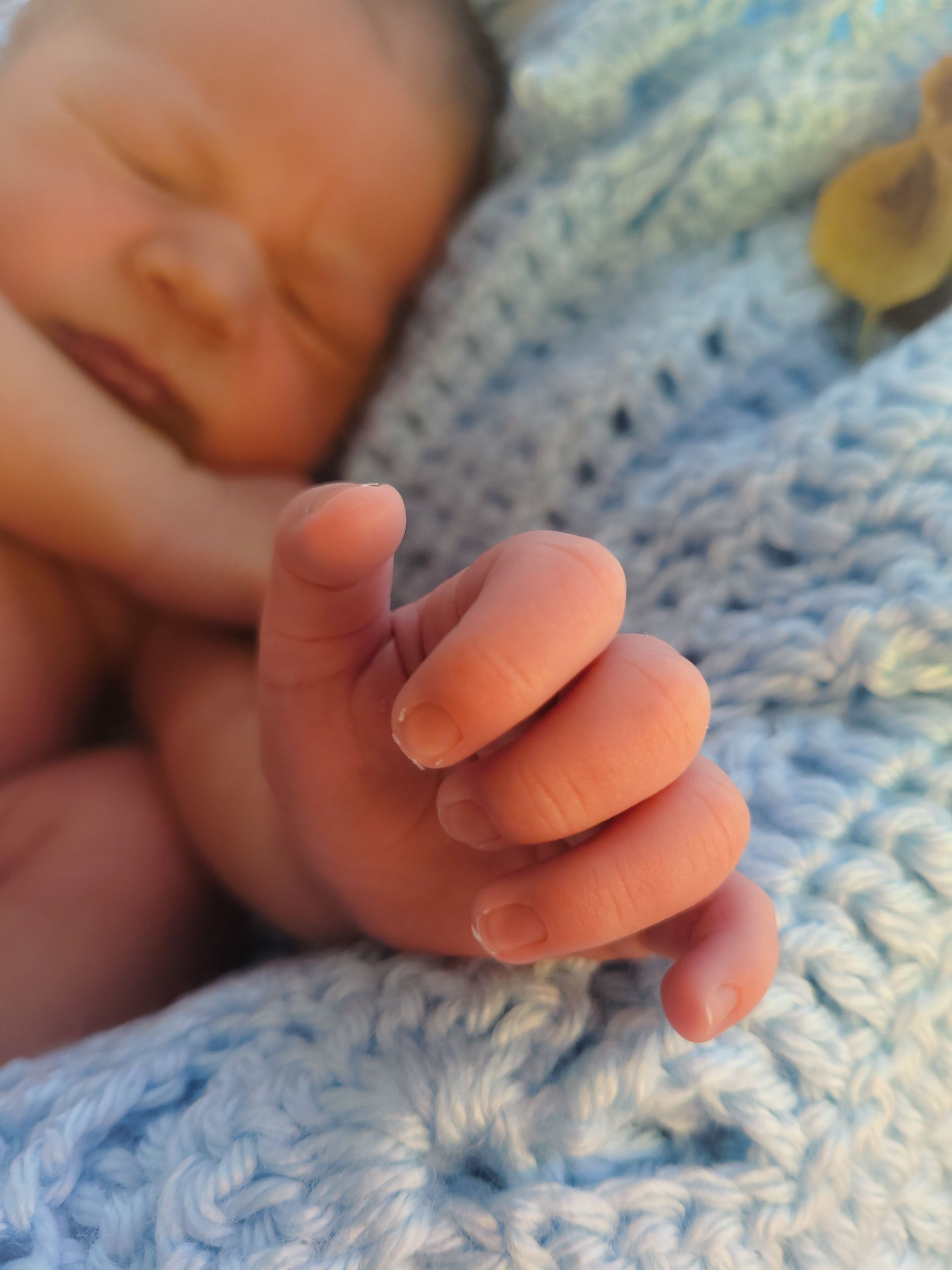 newborn hand and face in background
