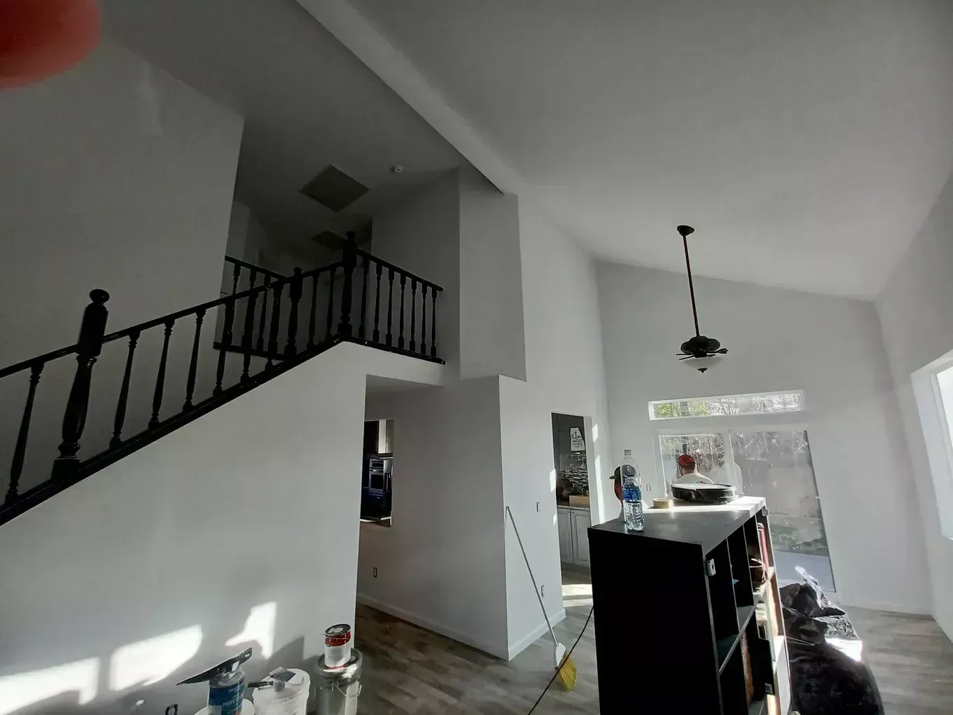 Bright open staircase and dining area with white walls, black railings, and large windows