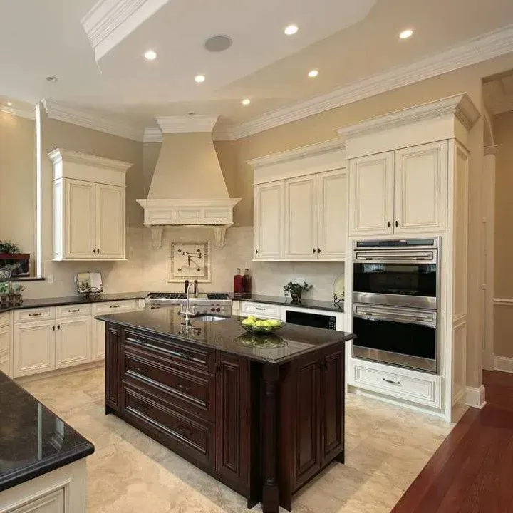 Bright luxury kitchen with dark island, white cabinets, and built-in ovens