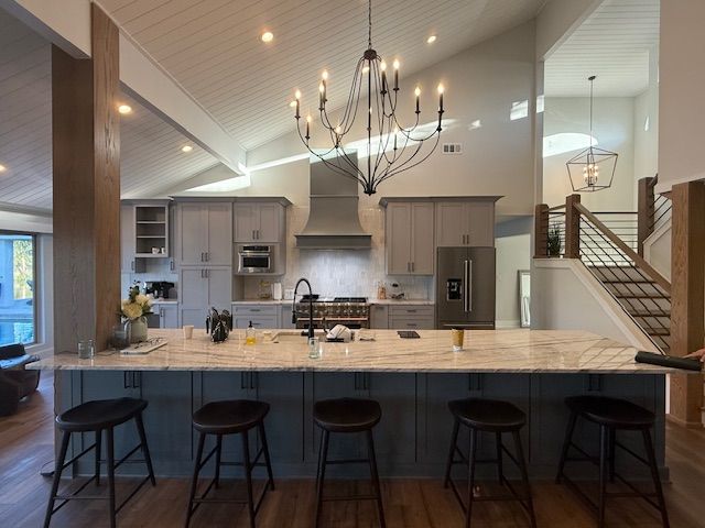 Modern kitchen with a large island, gray cabinets, chandelier, and staircase.