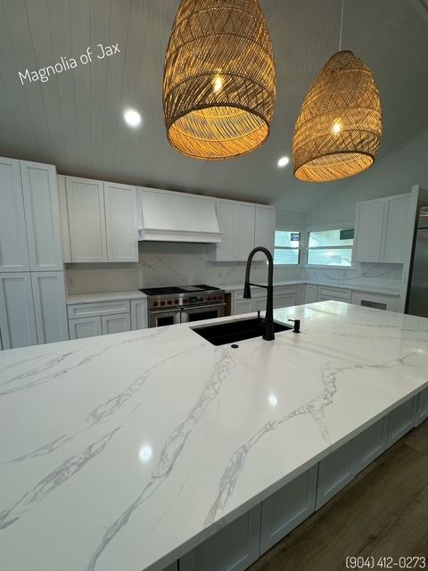 Modern kitchen with a white countertop island, white cabinets, and woven pendant lights.