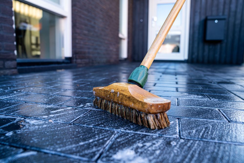 Broom Scrubbing a Wet, Dark Gray Brick Patio — Cairns Local Cleaning Services in Edmonton, QLD