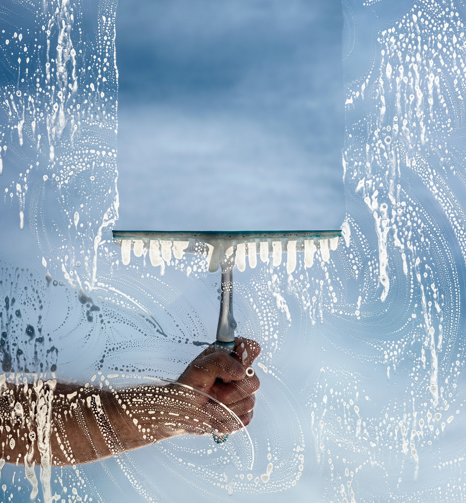 Hand Using a Squeegee to Clean a Window — Cairns Local Cleaning Services in Woree, QLD