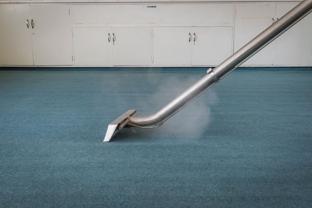 Steam Cleaning a Teal Carpet With a Silver Nozzle, Producing Vapor — Cairns Local Cleaning Services in Woree, QLD