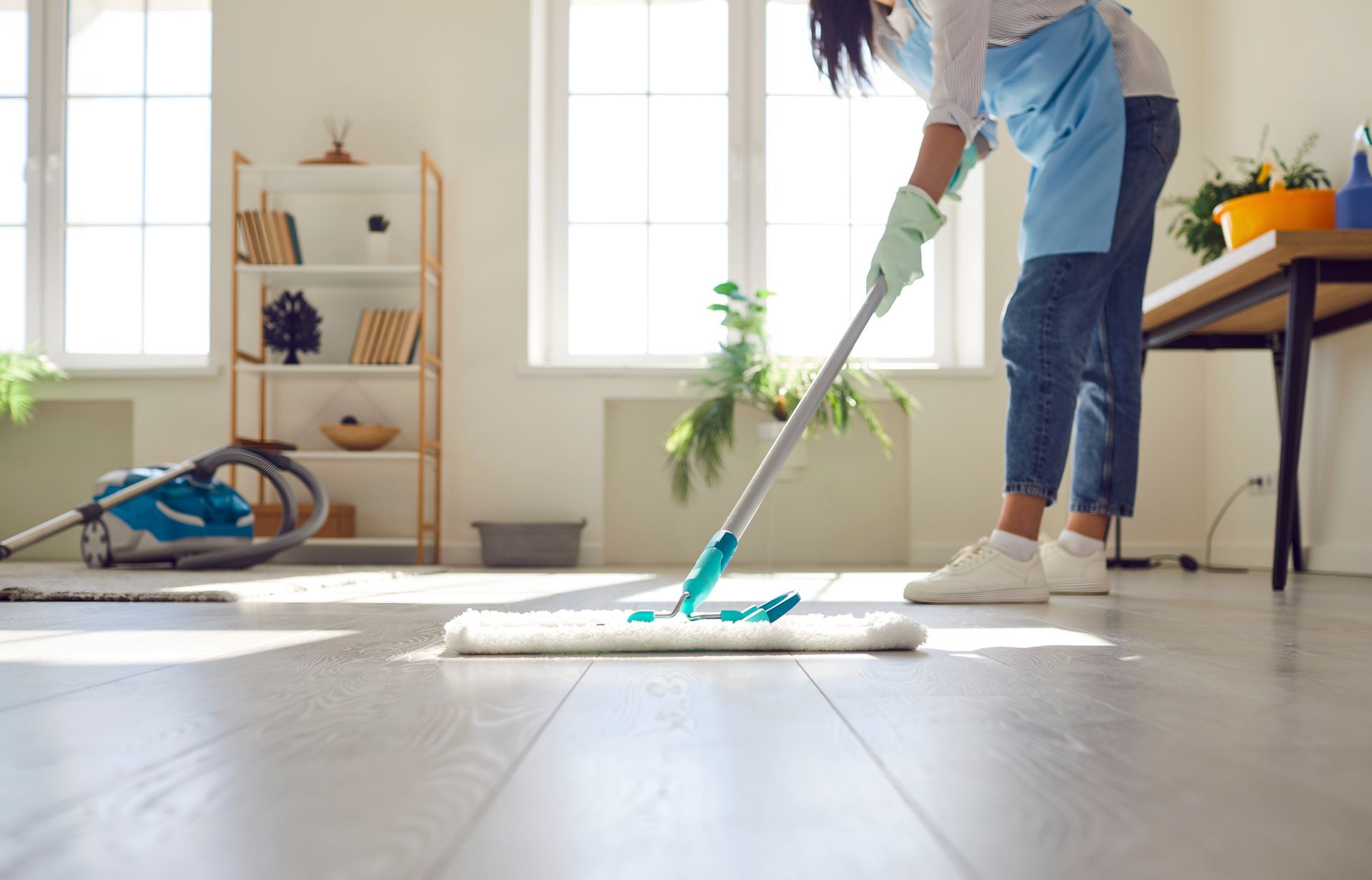 Woman Mopping a Wood Floor in a Brightly Lit Room — Cairns Local Cleaning Services in Woree, QLD