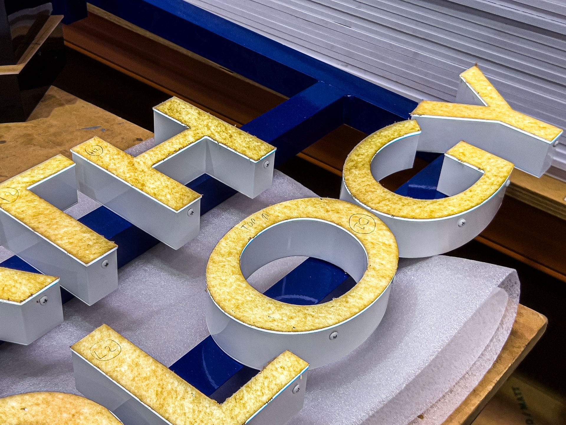 Close-up of illuminated channel letters for a sign in a fabrication workshop. Close-up of illuminated channel letters for a sign in a fabrication workshop.