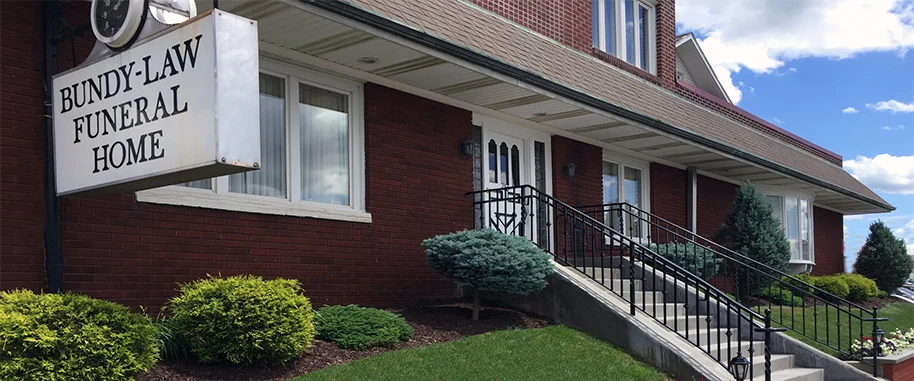 The front door of a house with a porch and plants in front of it.