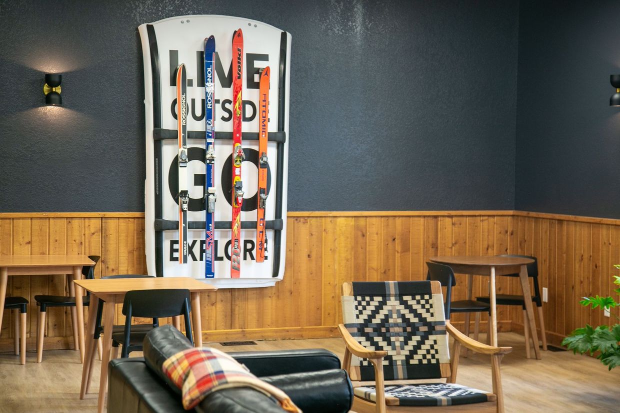 Cozy lounge with a “Get Outside Go Explore” wall sign, chairs, tables, and wood-paneled walls.